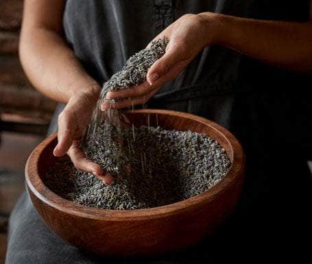 Hands sifting dried lavender buds into a wooden bowl | Lavender Shop | Sonoma Lavender